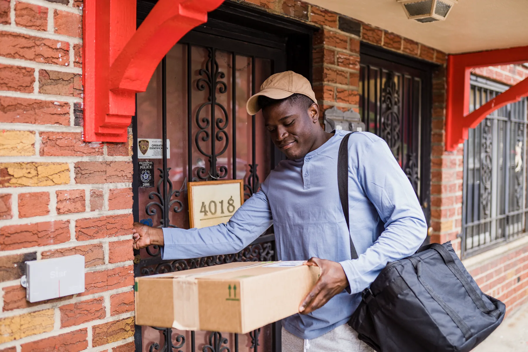 Courier carrying a cardboard parcel to a residential front door