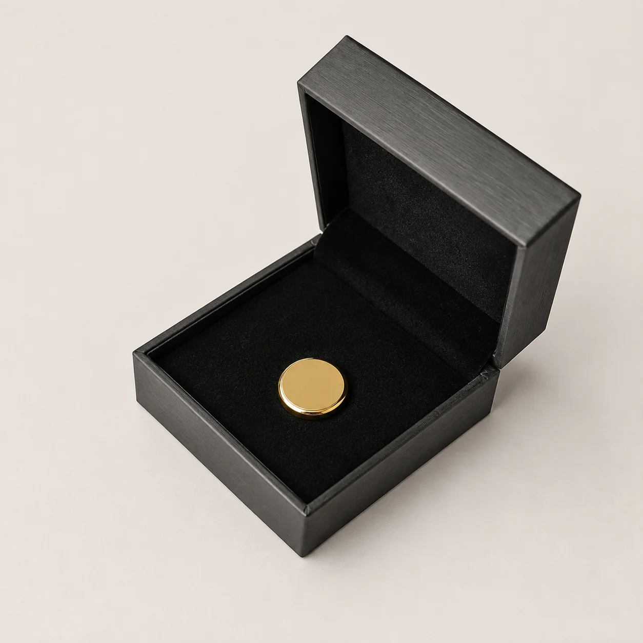 Open rigid black gift box with a gold pin in a foam insert