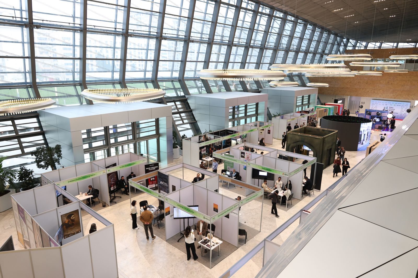 Visitors meeting at exhibition booths inside a spacious trade show hall